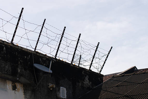 istock Barbed wire installed along the top of a concrete wall. 2224750804