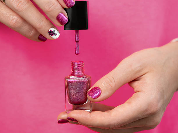 istock Pink manicure hands has purple nail polish bottle 2224755146