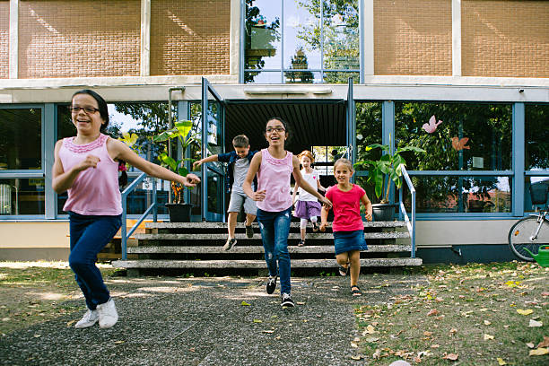 istock a group of elementary school students runs out of school for recess 2224758313
