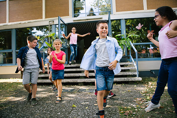 Jumping rope. Boys holding jump rope and joyful jumping girl spending time in park on sunny day