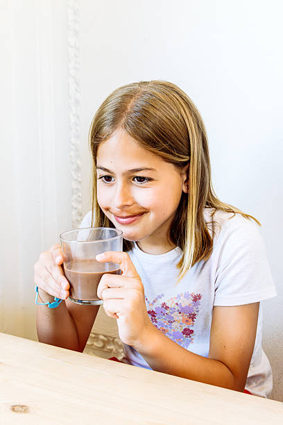 istock Smiling girl drinking chocolate milk at home 2224761653
