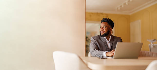 istock Male manager looking away and thinking business ideas while working over laptop at desk by wall in office 2224764313