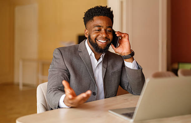 istock Businessman smiling and discussing with customer on phone call while using laptop at desk in office 2224764333