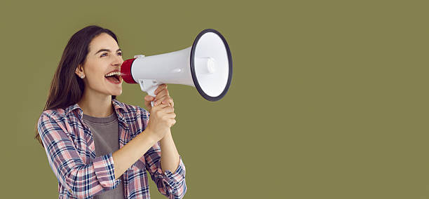 istock Happy young woman shouting into megaphone making announcement 2224764598