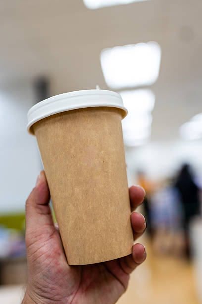 istock Brown paper coffee cup with a white lid on hand 2224768827