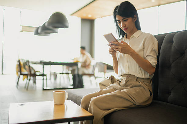 istock Relaxed businesswoman using smartphone at coffee shop with coffee cup on table. 2224769067