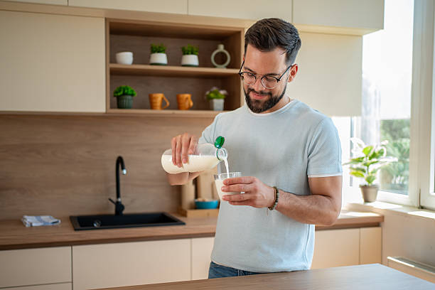 istock Young man pouring milk into glass in modern kitchen 2224769095