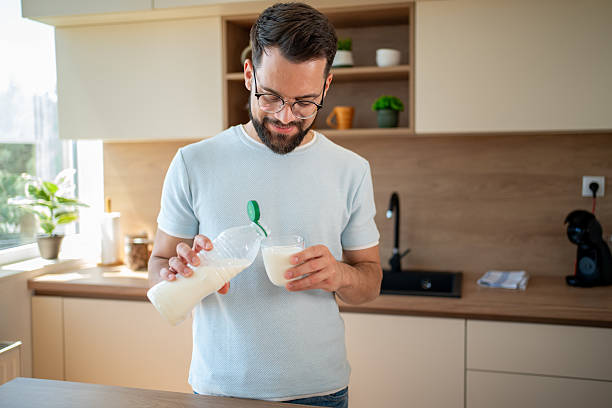 istock Young man pouring milk into glass in kitchen 2224769119