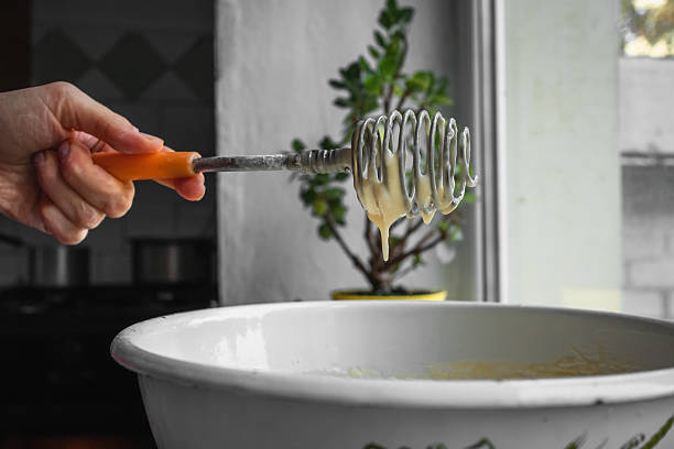 Biscuit preparation process. A woman's hand holds a whisk to whip the dough over a white plate.
