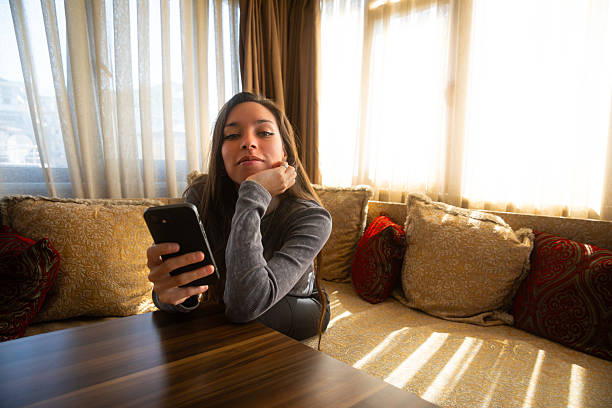 istock Young woman relaxing while using smartphone indoors 2224774671