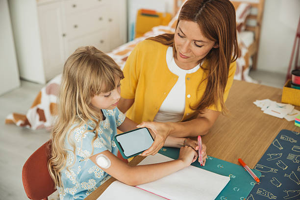 istock Mother checking glucose level on daughter's glucose meter 2224777388