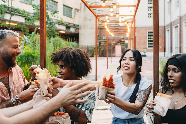 istock Group of friends eating pizza outdoors in urban setting 2224782712