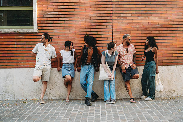 istock Young people leaning against a brick wall are enjoying their time together 2224783575