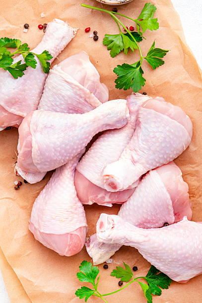 istock Raw chicken legs on parchment with pepper, salt and parsley. Top view 2224785416