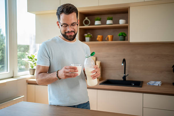 istock Young man pouring milk into glass in kitchen 2224793383