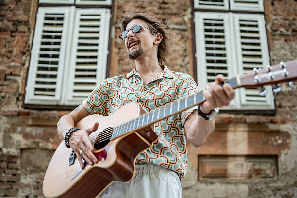 A street musician plays the guitar, entertains people in the city square. High quality photo