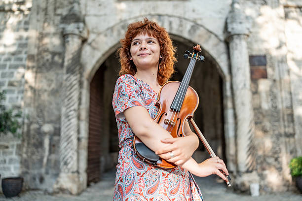 Young woman street artist playing violin on public square and enjoying it