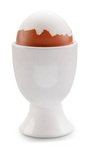 istock Boiled partly peeled chicken egg in the egg cup on white background. File contains clipping paths. 2224807231