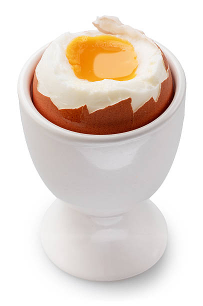 Soft -boiled partly peeled chicken egg with soft yolk in egg cup on white background. File contains clipping paths.