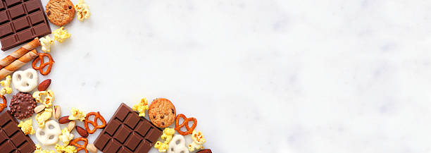 istock Sweet and salty snacks corner border over a white marble banner background 2224807795