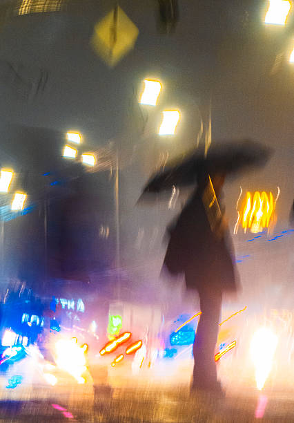 istock Pedestrian walking in the rain with umbrella at night with blurred lights 2224809721