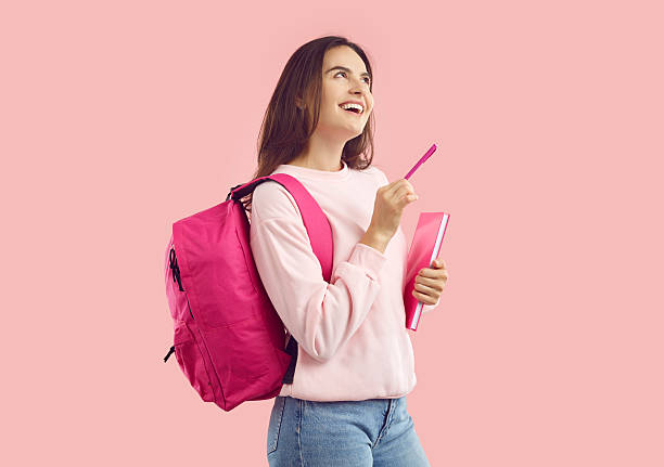istock Joyful female student with pen and notebook pondering interesting idea isolated on pink background. 2224809835