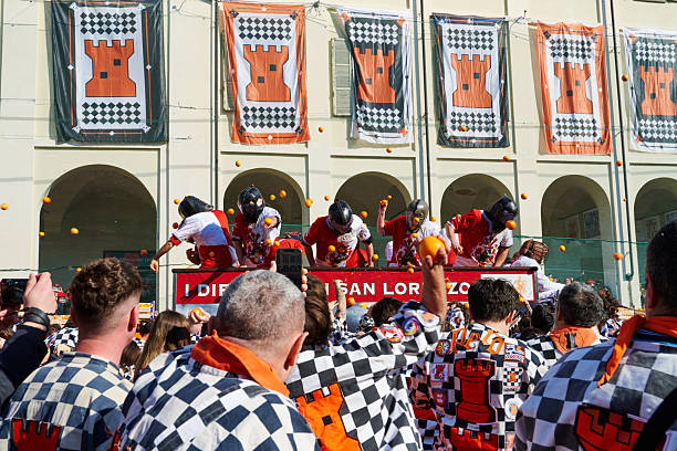 Ivrea, Italy - March 02, 2025: groups in traditional dressing take part in the Battle of the Oranges, where a teams of orange handlers on foot throw oranges (representing old weapons and stones) against aranceri of the team \