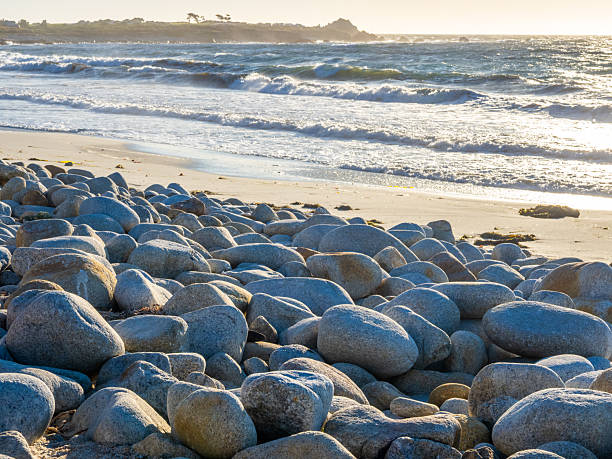 Sunlit rocks and waves at Pebble Beach during golden hour