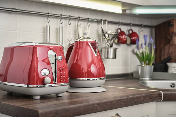 Red toaster and electric kettle in retro slile on tabletop in kitchen interior.