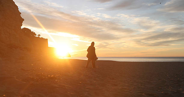 istock Young woman explores empty beach at sunrise 2224828241
