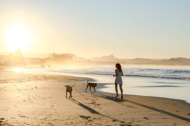 istock woman on beach with dogs 2224835234