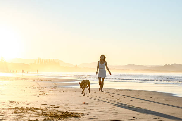 istock woman on beach with dogs 2224835348