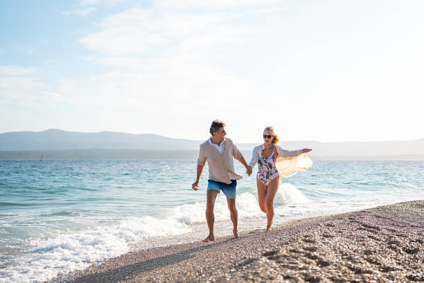 istock Joyful Mature Couple Running Along Mediterranean Beach Shore In Bright Sunlight 2224836904