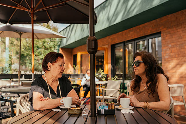 istock Two elderly friends chatting at an outdoor cafe 2224839701