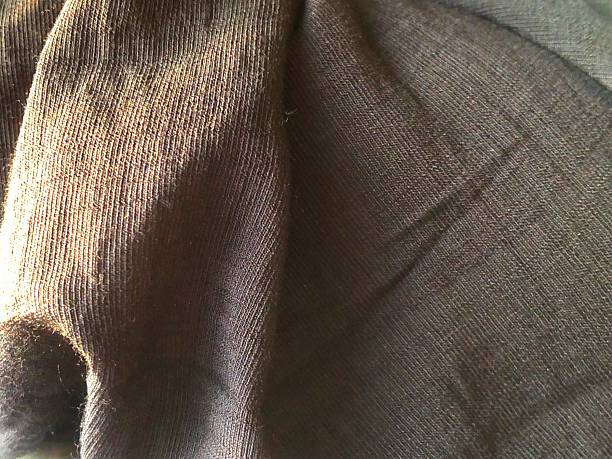 This image captures a close-up of a dark brown, possibly black, fabric with a visible texture