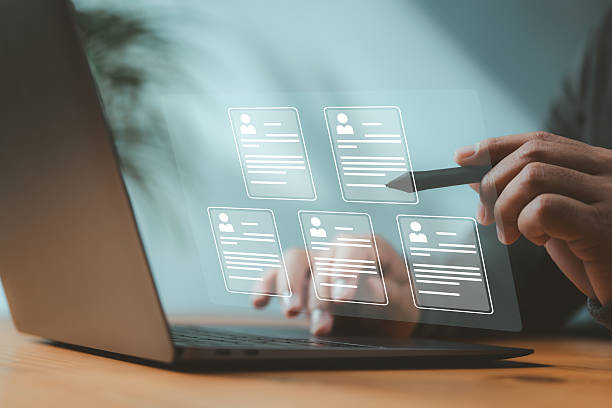 istock Recruiter browsing digital resumes on futuristic interface using a stylus and laptop. Concept of online hiring, tech-driven HR, and digital recruitment systems. 2224844288