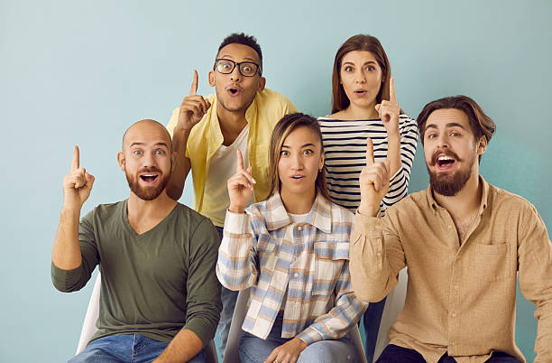 istock Group of multiracial young people having ideas pointing index fingers up on light blue background. 2224846676