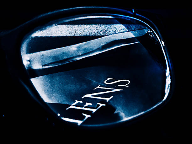 A highly stylized, fine art close-up of a reflective optical lens, capturing abstract light and shadow interplay with crisp typography reading “LENS.” The image combines minimalism and macro detail, offering strong commercial appeal for use in concepts of vision, clarity, optics, creativity, technology, and abstract communication. This conceptual photograph balances modern design aesthetics with artistic depth, ideal for editorial, advertising, and fine art usage.