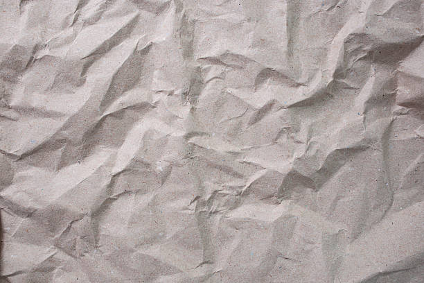 istock Gray recycled  paper sheet crumpled with shadowed wrinkles, soft focus close up, abstract texture 2224852842