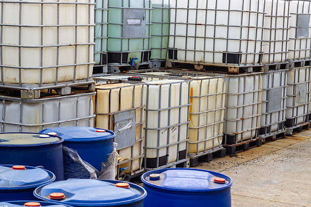 A collection of palletized IBCs and blue barrels in an outdoor industrial storage yard showcase the scale and functionality of logistics and supply chain management. These containers represent the