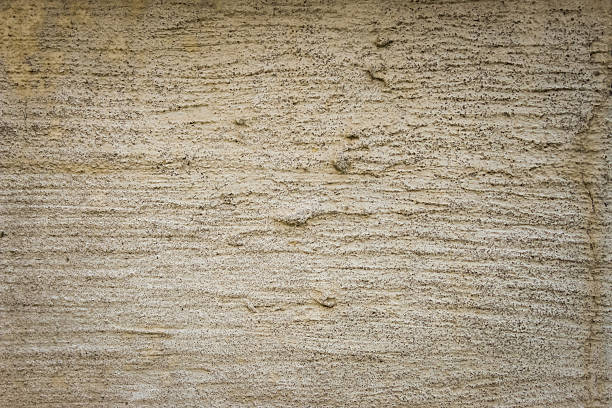 a rough, textured beige concrete surface, characterized by horizontal, wave-like patterns. weathered and rustic abstract background with copy space