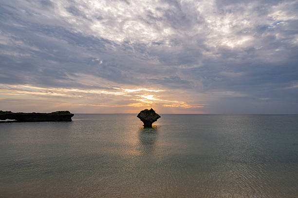 Sunset over the sea with a rock in the middle of the water