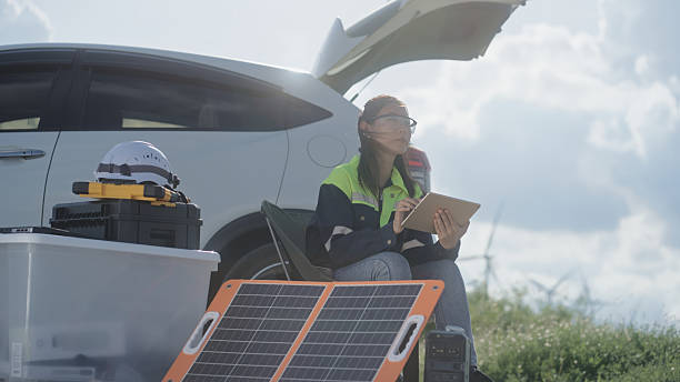Sustainable home owner using phone in the front yard, electric vehicle and solar panels visible