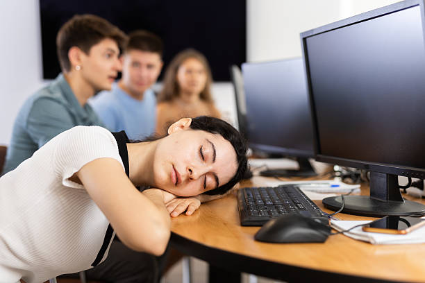 istock Exhausted girl student sits at table, puts head on crossed arms and sleeps after computer classes 2224863259