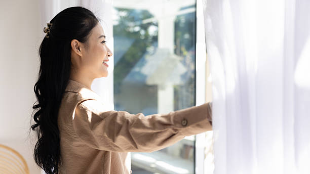 istock Asian woman opening curtains with joyful expression 2224864269