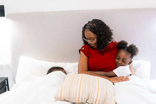 istock Mother hugging daughter while putting children to sleep in bed 2224866963