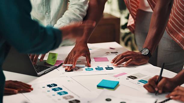 istock People, hands and planning with documents for design, strategy or brainstorming on office desk. Group, employees or creative designers working together with paperwork, notes or ideas at workplace 2224867440