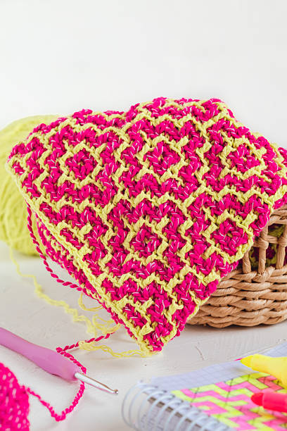 istock Workplace with bright pink yellow crochet fabric. Knitted texture with geometric design. Eco friendly handmade concept. 2224867544