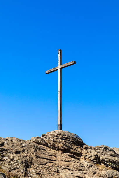 Three crosses sit on a rocky butte as they are silhouetted against a rising sun and symbolize the Crucifixion of Christ.  In the distance the sun creeps above the horizon.