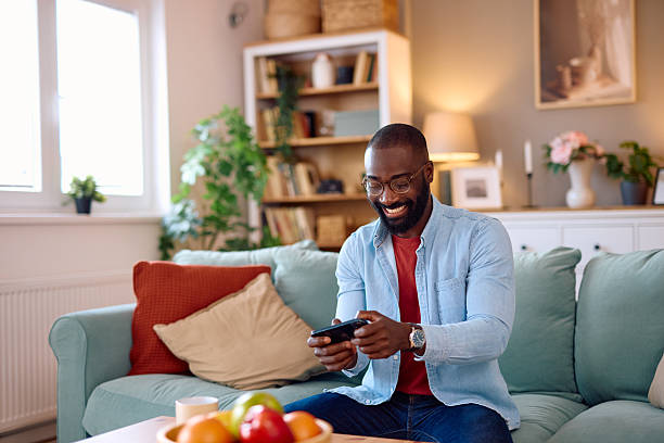 istock Young man playing mobile games at home sitting on the sofa 2224872301